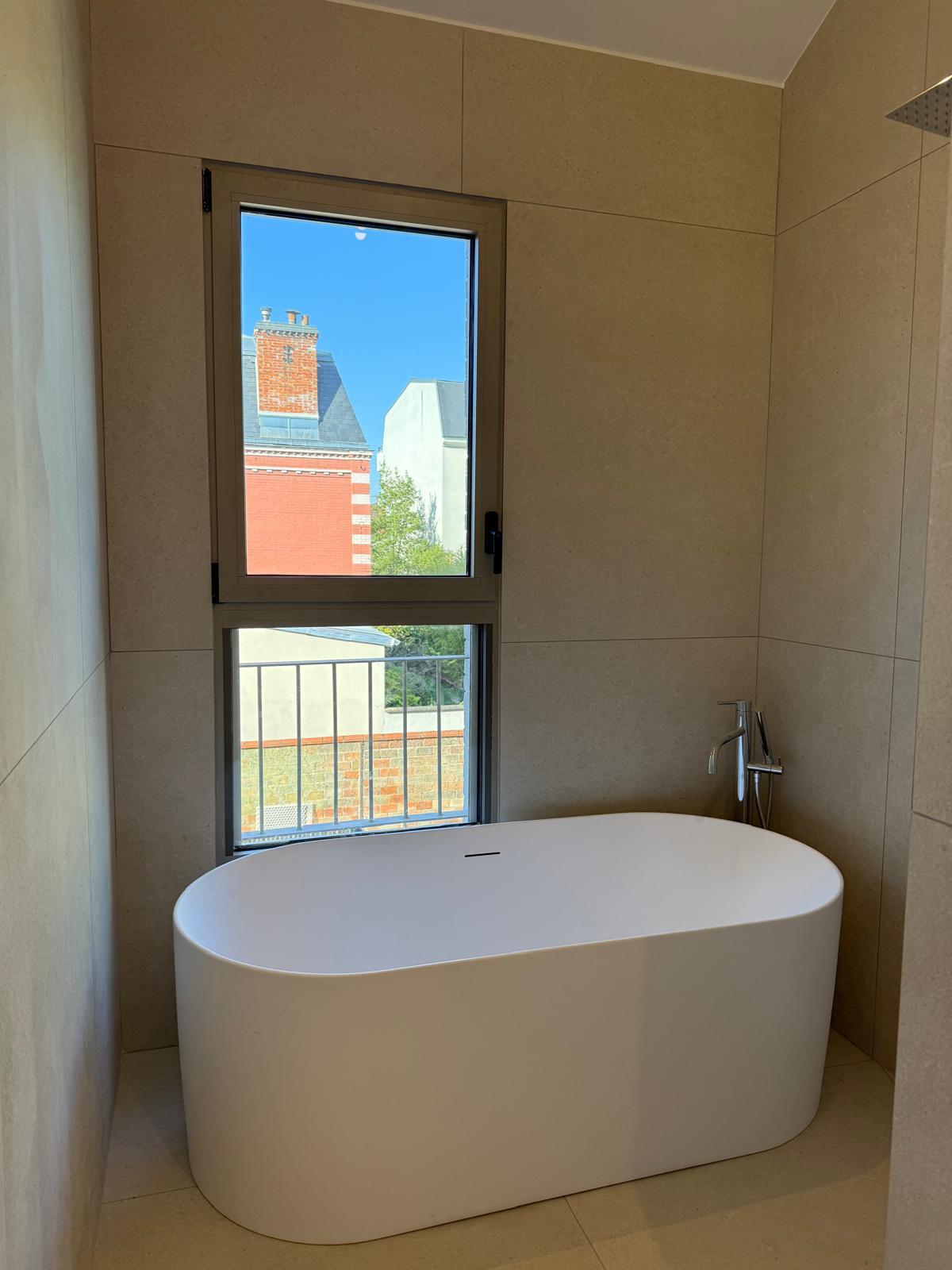 Baignoire îlot sous fenêtre avec vue sur les toits