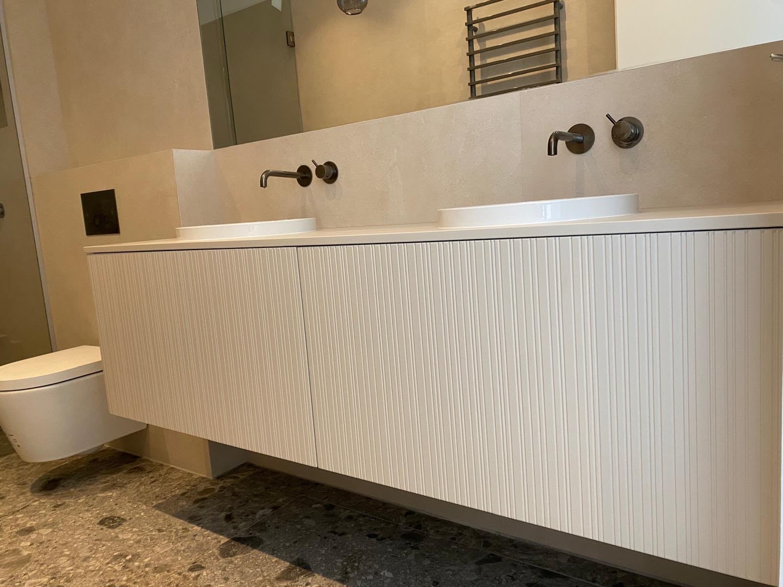 Double vasque sur meuble strié, douche vitrée et toilette suspendue